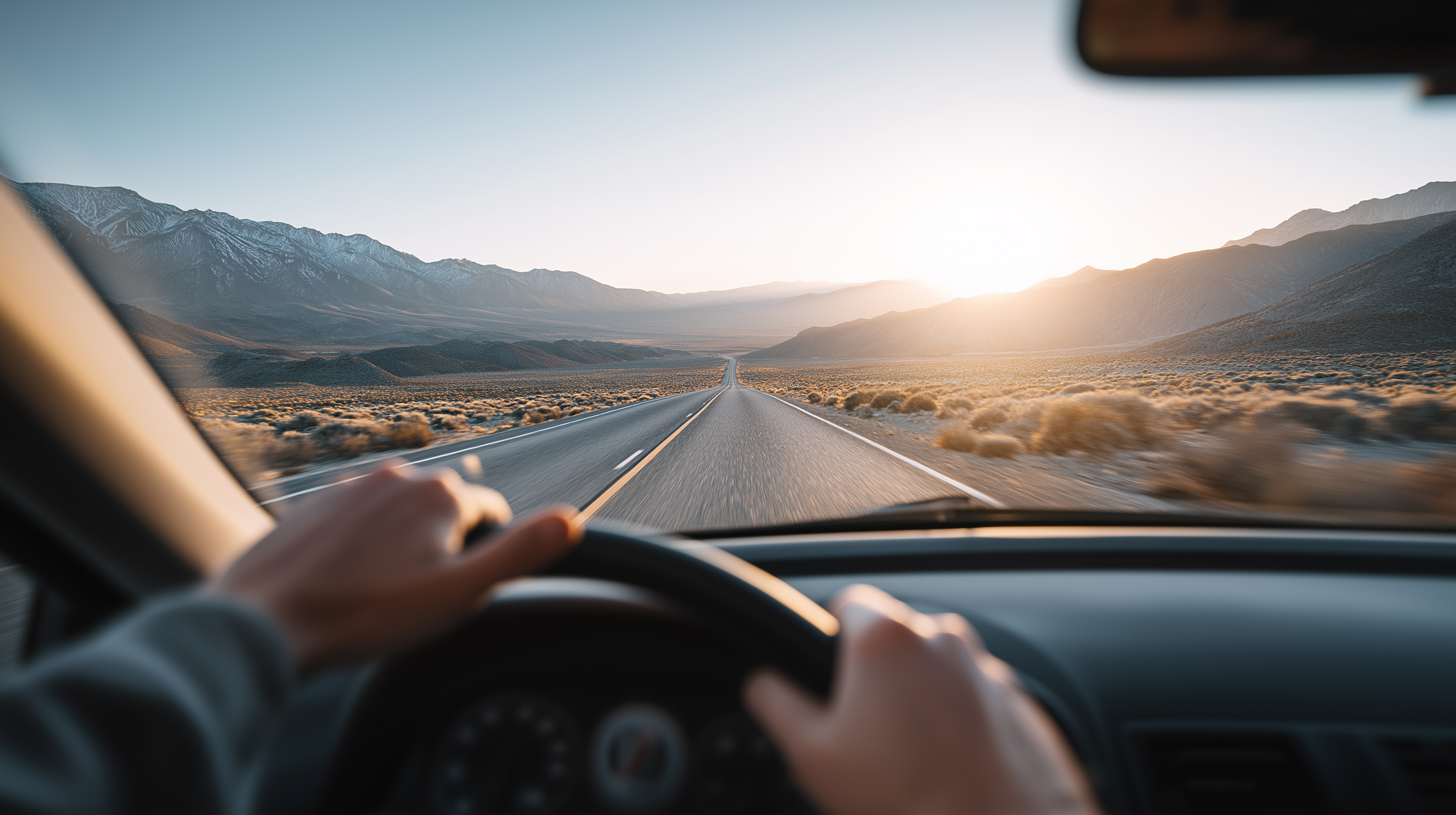 Driving an open desert road toward the sunrise